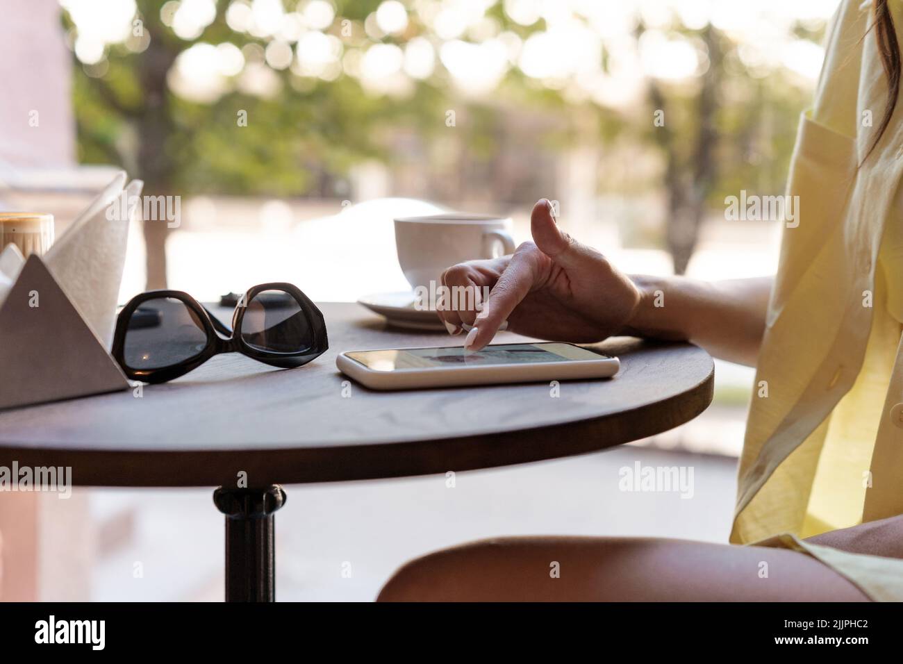 Nahaufnahme einer Frau, die mit einem Mobiltelefon in einem Café sitzt Stockfoto