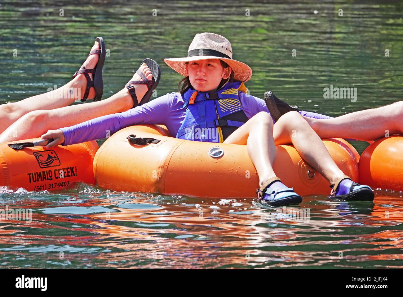 Junge Menschen treiben den Deschutes River in Bend, Oregon, auf leuchtend orangefarbenen Floatrohren und versuchen, der 100-Grad-F-Hitzewelle zu entkommen, die den pazifischen Nordwesten durchfegt. Stockfoto