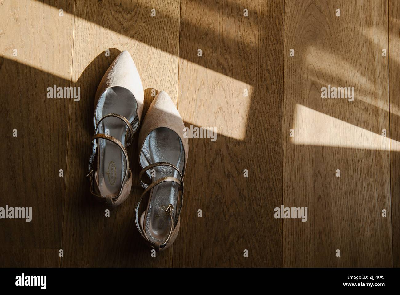 Ein Blick von oben auf klassische beige Schuhe auf einem Holzboden mit Sonnenlicht Stockfoto