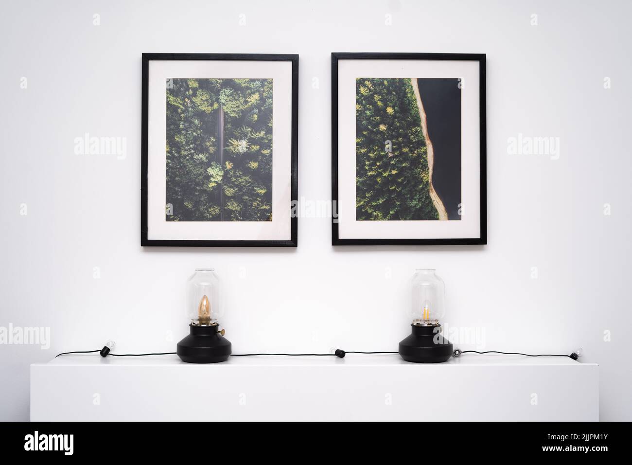 Zwei schwarze Bilderrahmen hängen an der Wand im Raum über dem Bettgestell Stockfoto