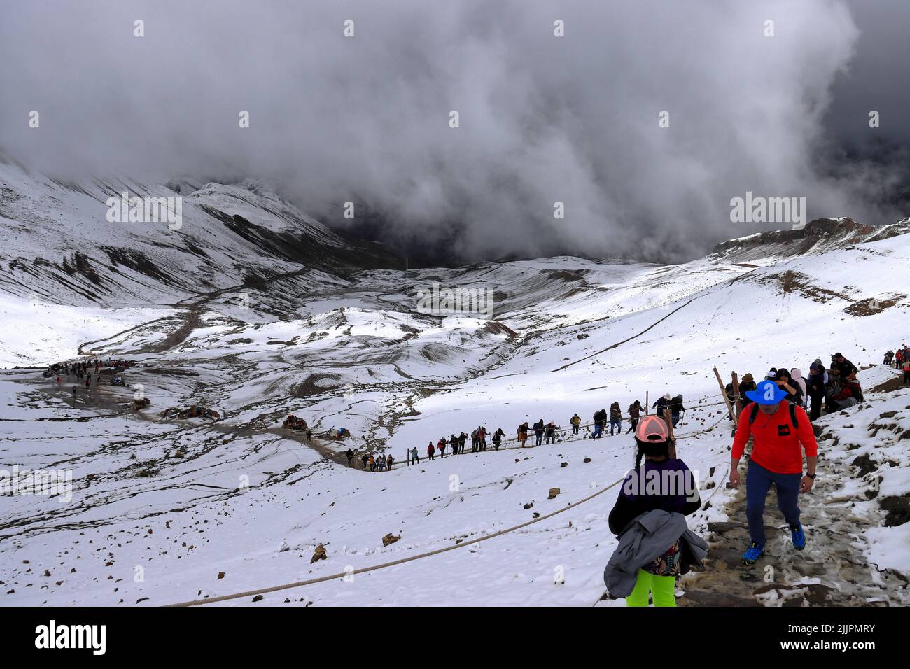 Eine Gruppe von Menschen wandern durch die Schneelandschaft zum Rainbow Mountain Vinicunca in den Anden Perus bei Cusco Stockfoto