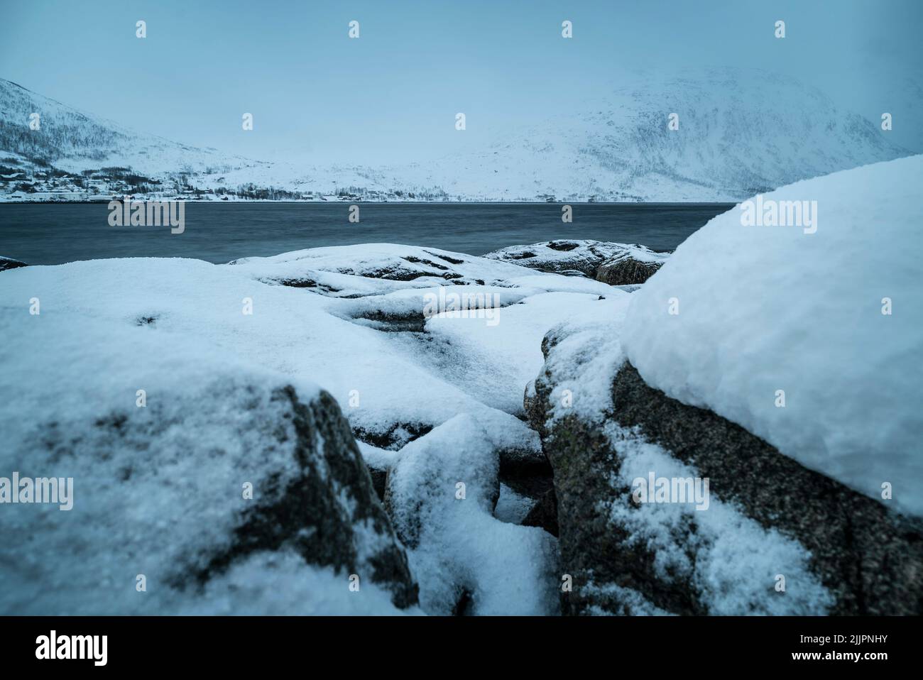 Eine schöne Aufnahme von schneebedeckten Felsen im Ersfjord in der Nähe der Insel Kvaloya, Norwegen bei bewölktem Wetter Stockfoto