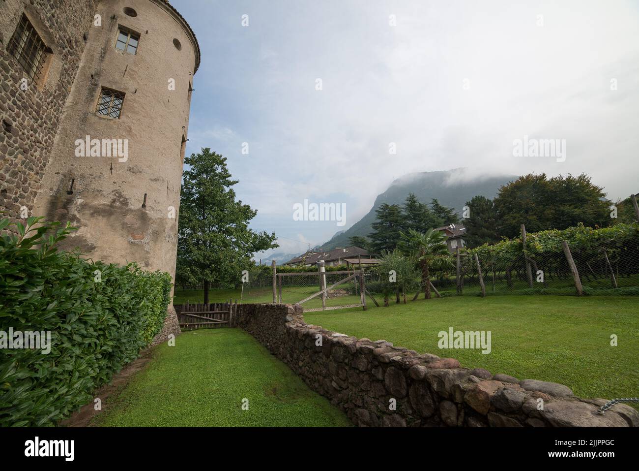 Ein schöner Hinterhof eines historischen Steingebäudes mit einem nebligen Berg im Hintergrund Stockfoto