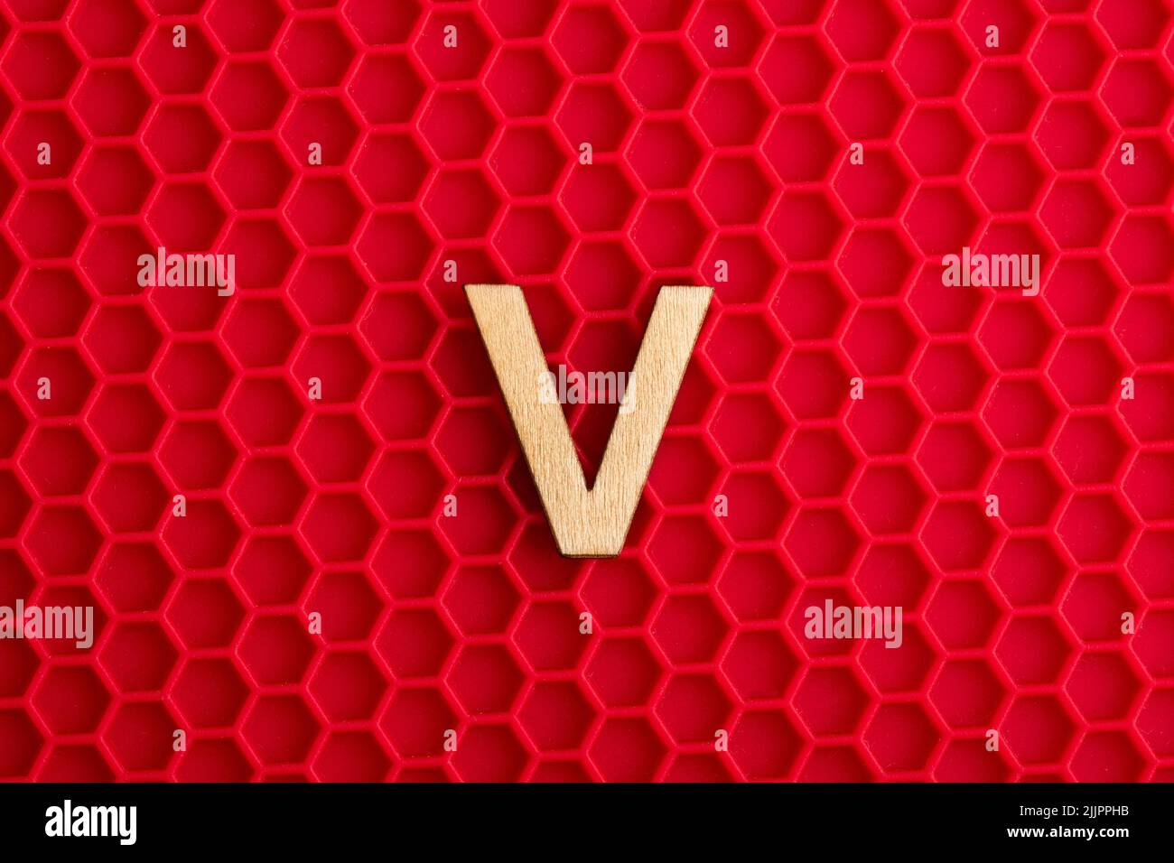 Großbuchstabe V - Weißes Stück auf Silikonhintergrund mit roten Sechsecken Stockfoto