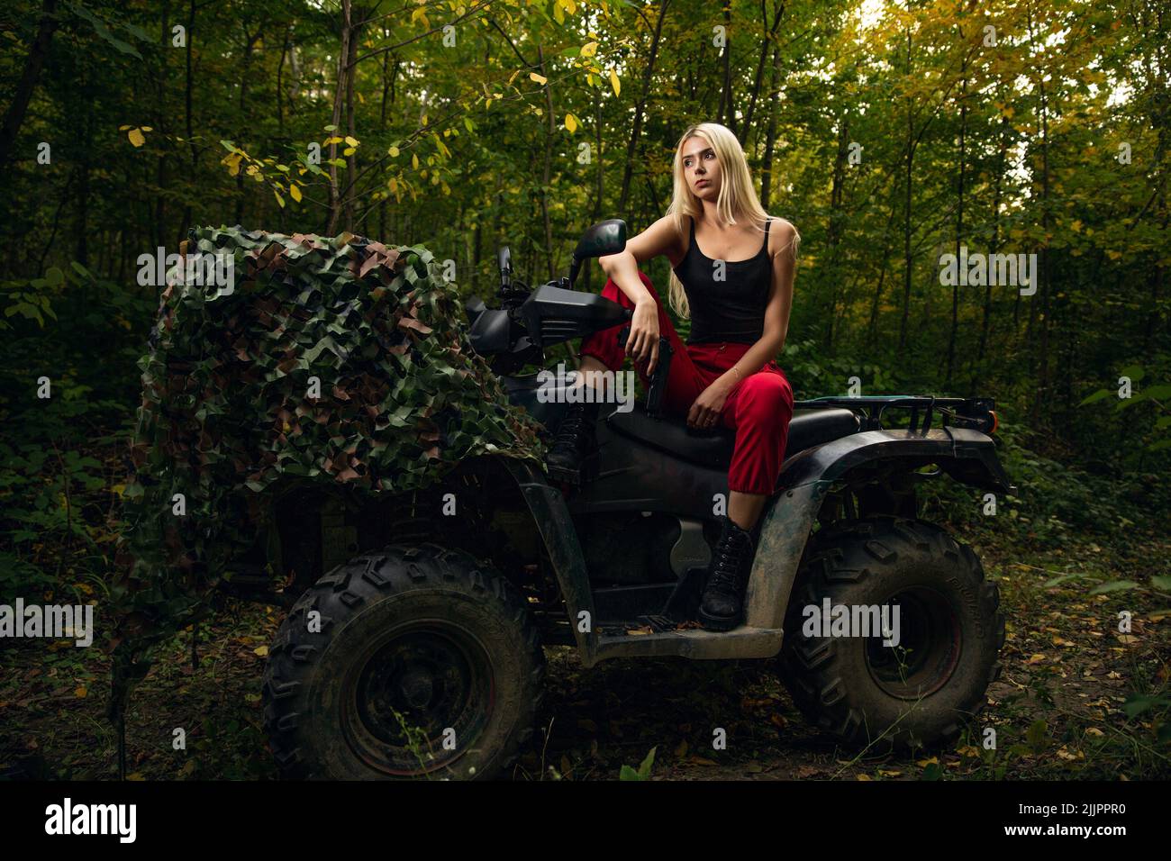 Ein Porträt einer kaukasischen blonden Frau, die auf einem Fahrrad in einem Wald sitzt Stockfoto