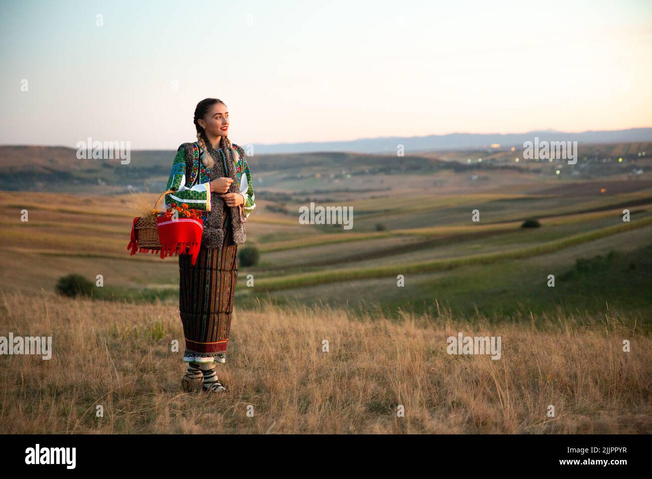 Eine schöne Aussicht auf eine junge Frau mit rumänischer traditioneller Kleidung, die auf dem Feld steht Stockfoto