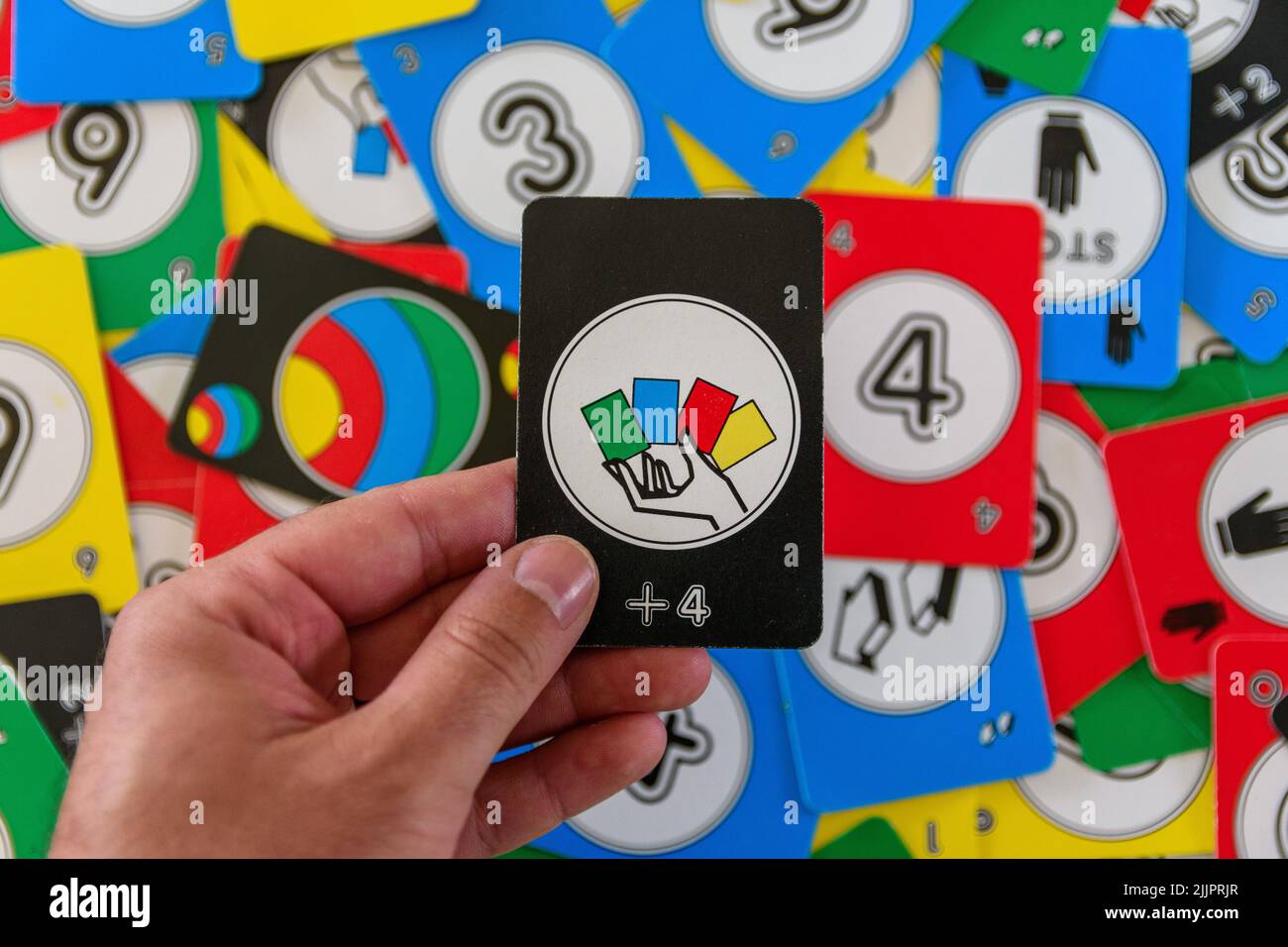 Eine Hand mit einer schwarzen Uno-Karte zieht vier Zeichen ab Stockfoto