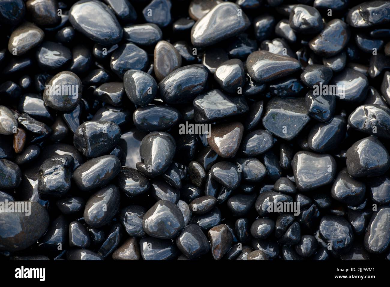 Nahaufnahme von schwarzen vulkanischen Kieselsteinen am Strand von Mavra Volia auf der Insel Chios in Griechenland. Stockfoto