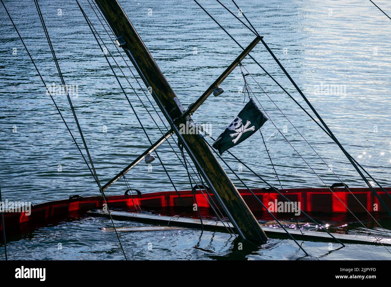 Der Mast eines versunkenen Bootes mit einer Piratenfahne, die aus dem Wasser herausragt Stockfoto