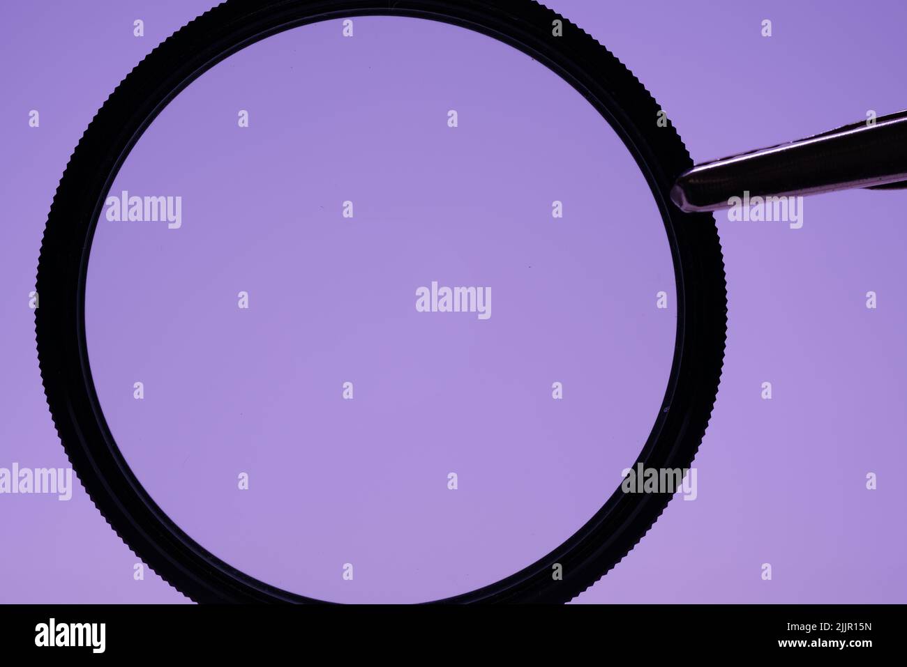 Eine Nahaufnahme einer schwarzen Lupe auf einem hellvioletten Hintergrund Stockfoto