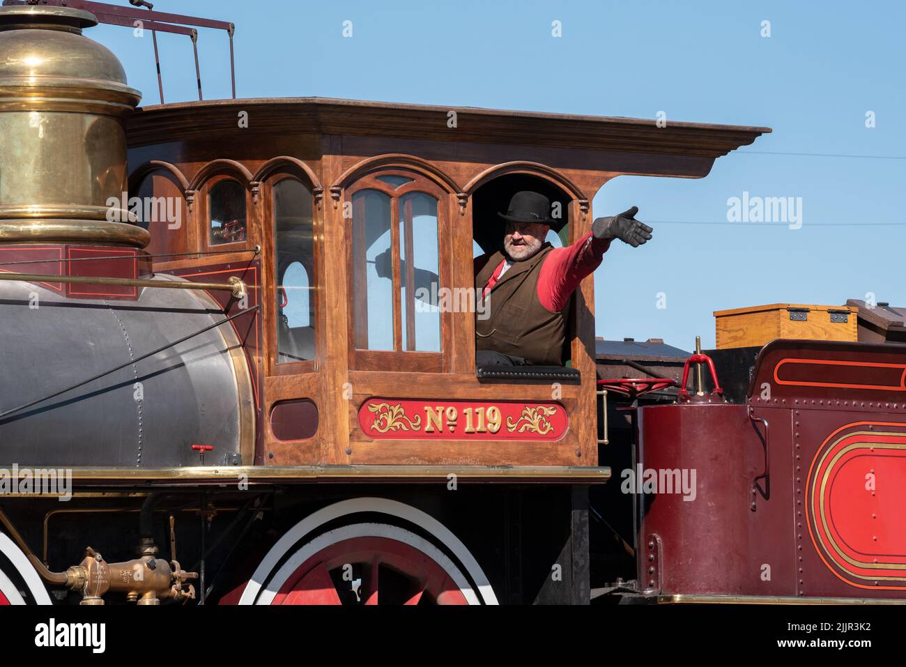 Ingenieur winkt aus dem Fahrerhaus der Lokomotive 119 während der Demonstration im Golden Spike National Historic Park, Utah. Stockfoto