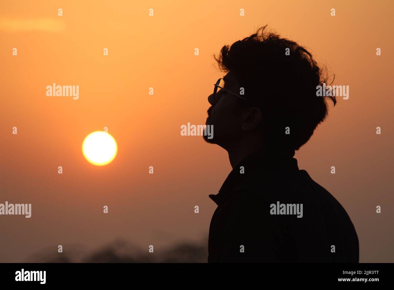 Eine Silhouette eines jungen südasiatischen Jungen mit Brille bei Sonnenuntergang -Inspiration und Motivationskonzept Stockfoto