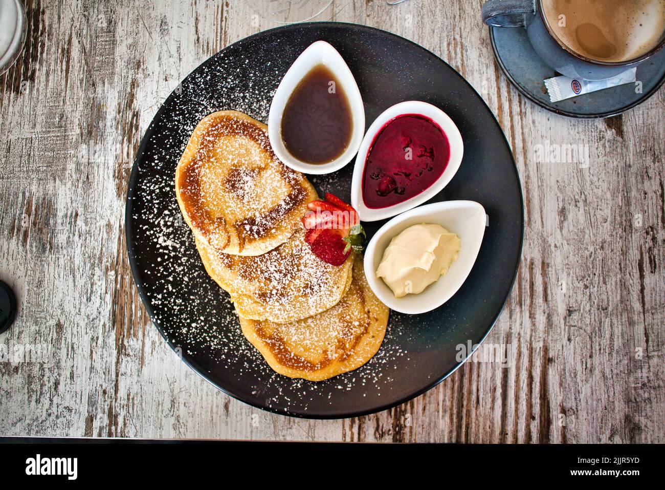 Ein Blick von oben auf süße Pfannkuchen auf einem Teller mit Marmelade und Saucen in Schüsseln Stockfoto