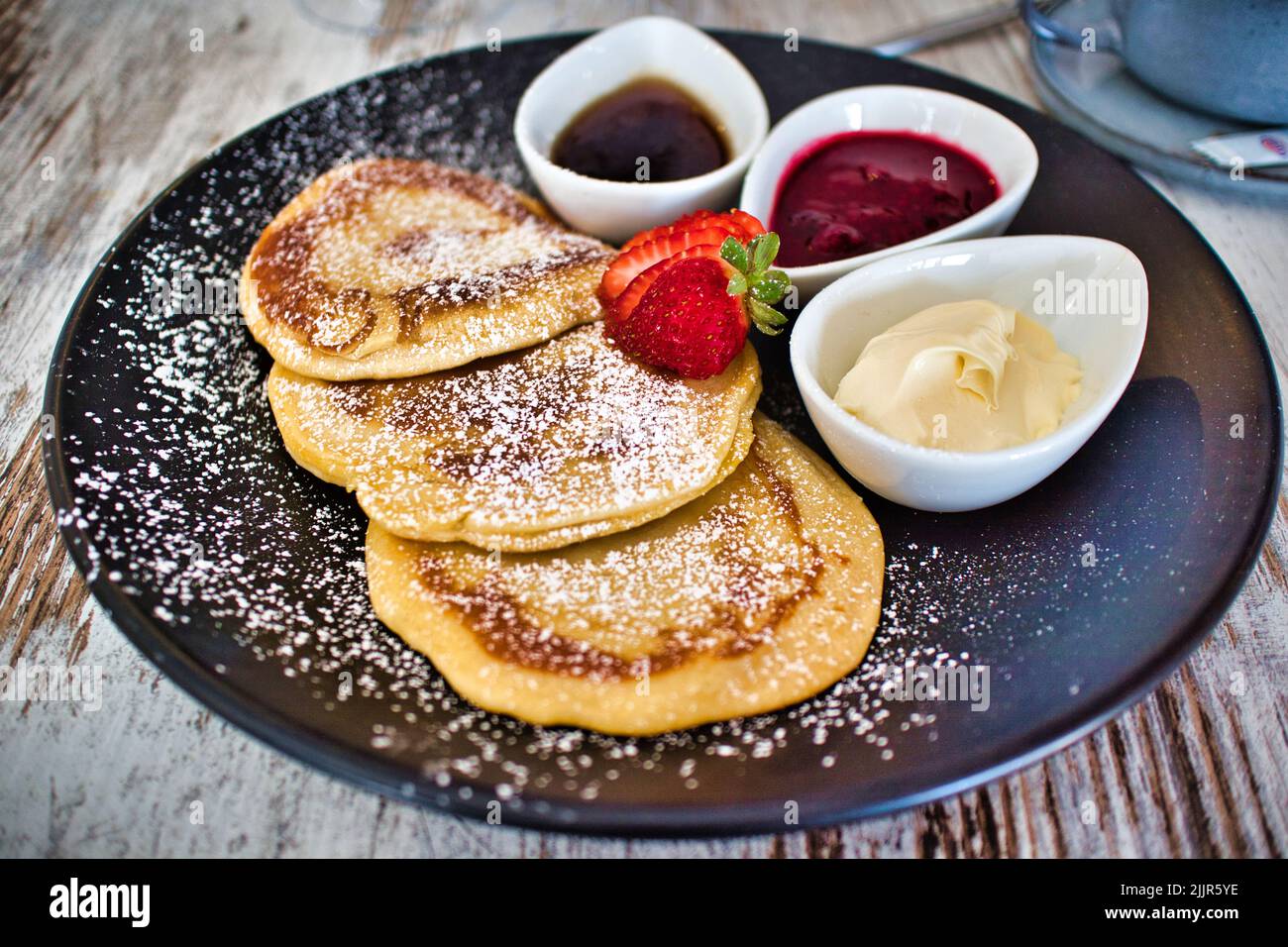 Eine Nahaufnahme von leckeren Pfannkuchen mit verschiedenen Saucen und Puderzucker serviert Stockfoto