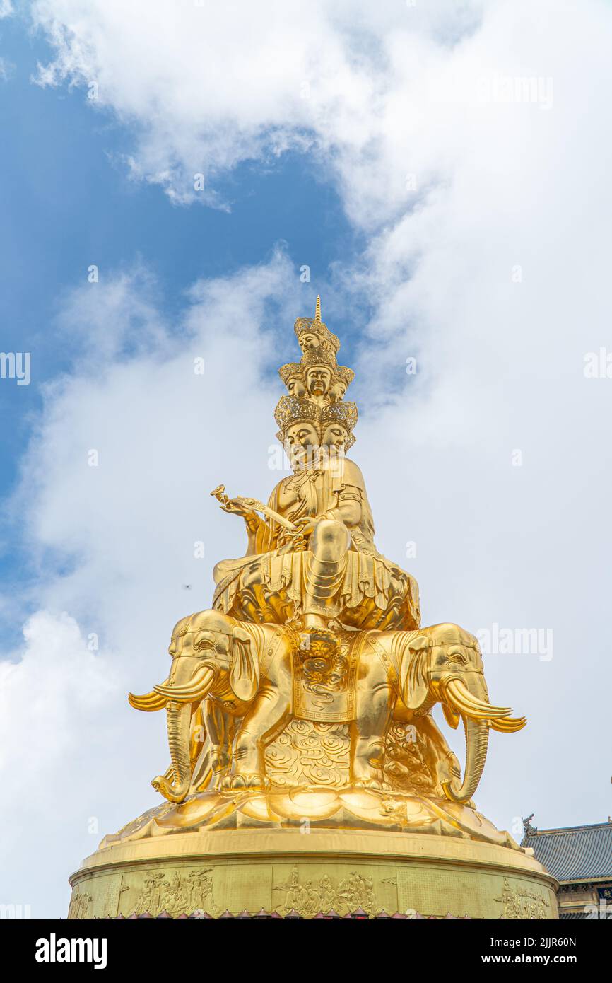 Eine vertikale Nahaufnahme einer goldenen Buddha-Statue auf blauem bewölktem Himmel Hintergrund Stockfoto