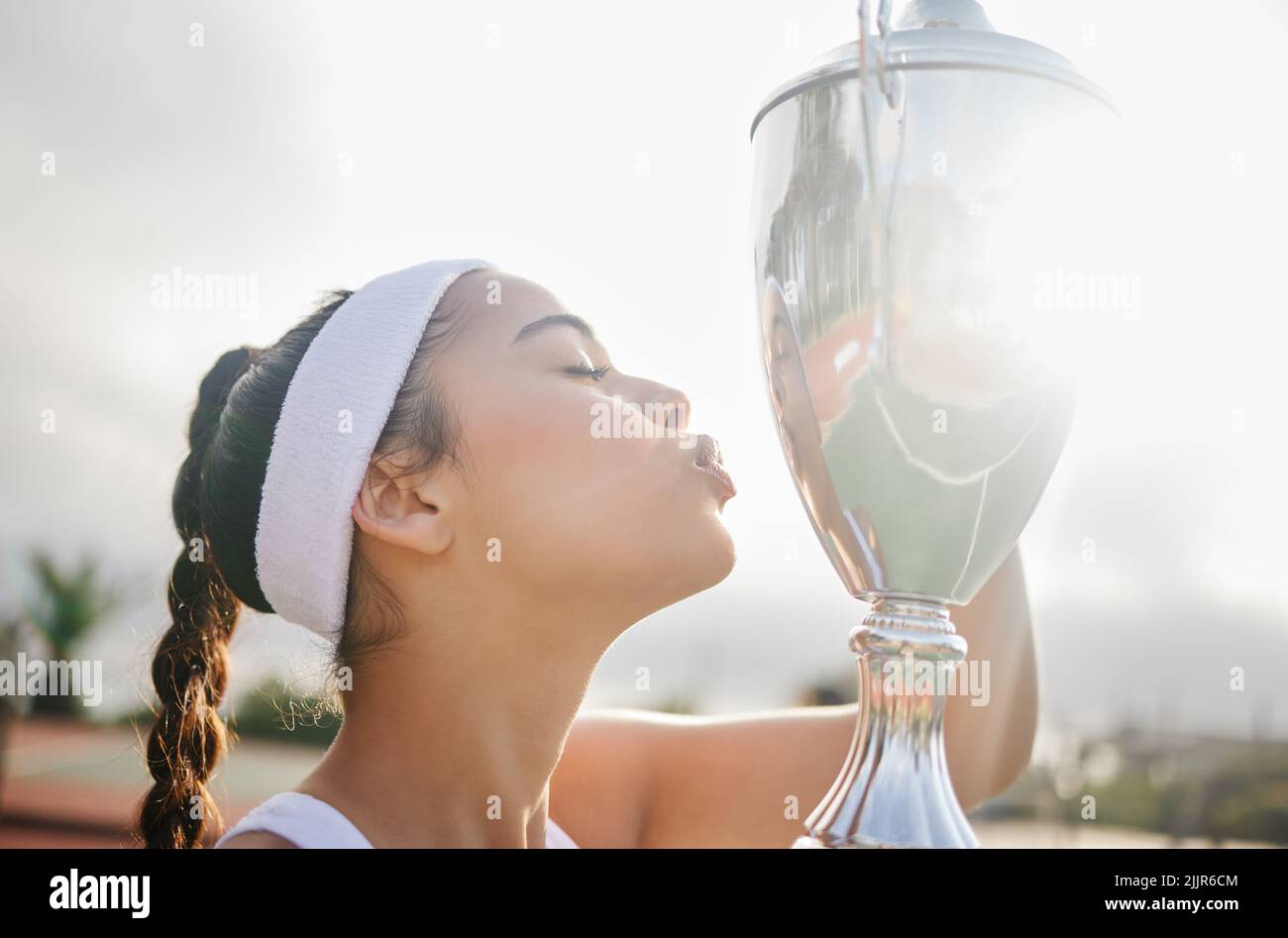 Gewinnen ist eine Art, sich auszudrücken. Ein attraktiver junger Tennisspieler hält eine Trophäe. Stockfoto