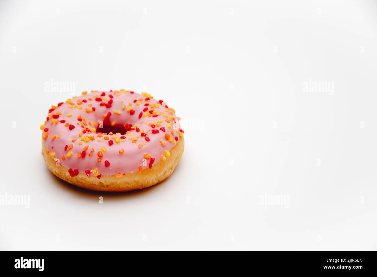 Eine Nahaufnahme eines rosa glasierten Donuts auf weißem Hintergrund mit Kopierfläche Stockfoto