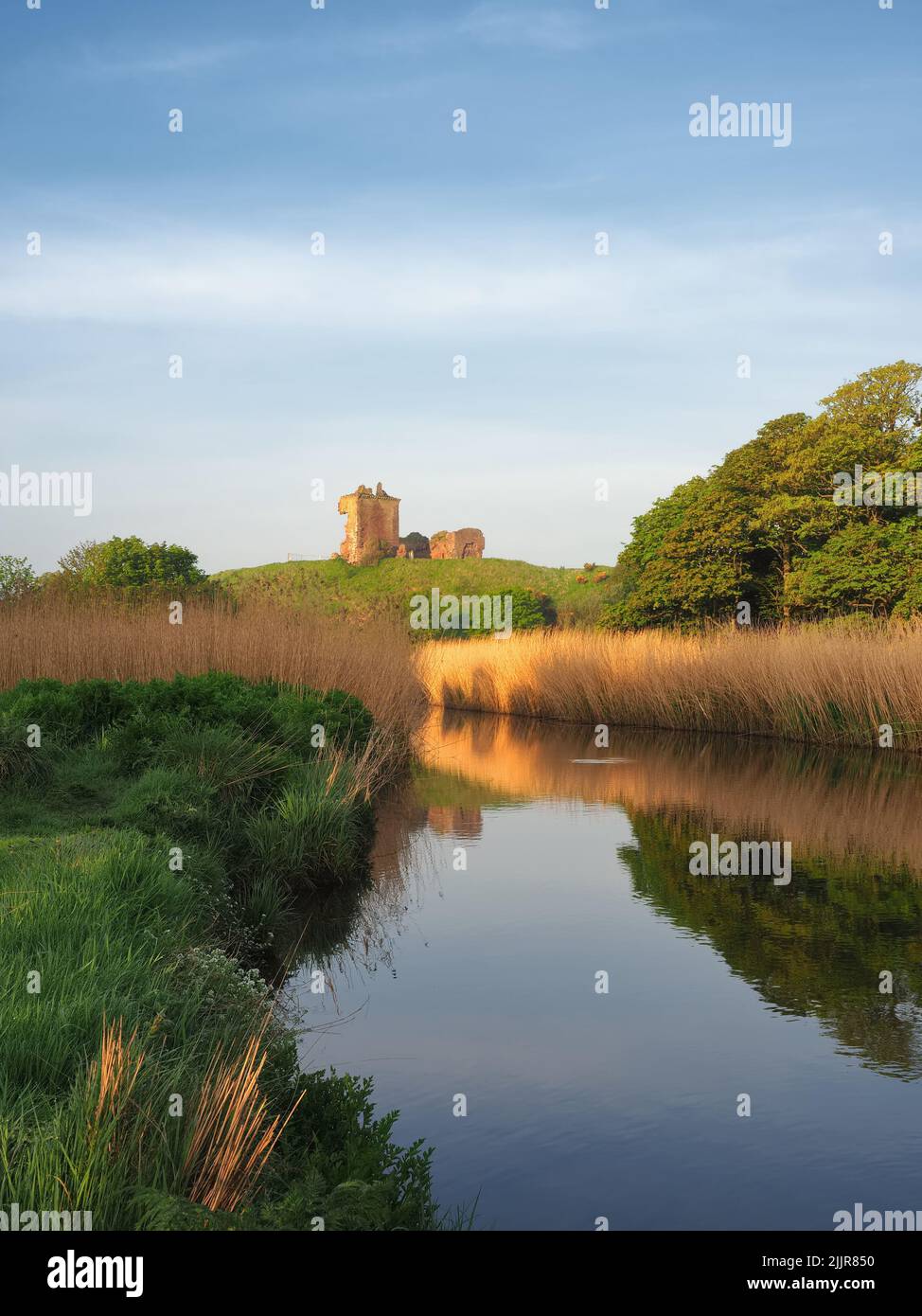 Eine schöne Aussicht auf einen Bach mit dem Roten Schloss von Lunan im Hintergrund am Morgen Stockfoto