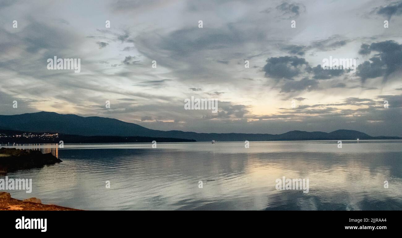 Eine schöne Aussicht auf einen See, umgeben von Bergen unter dem wolkigen blauen Himmel Stockfoto