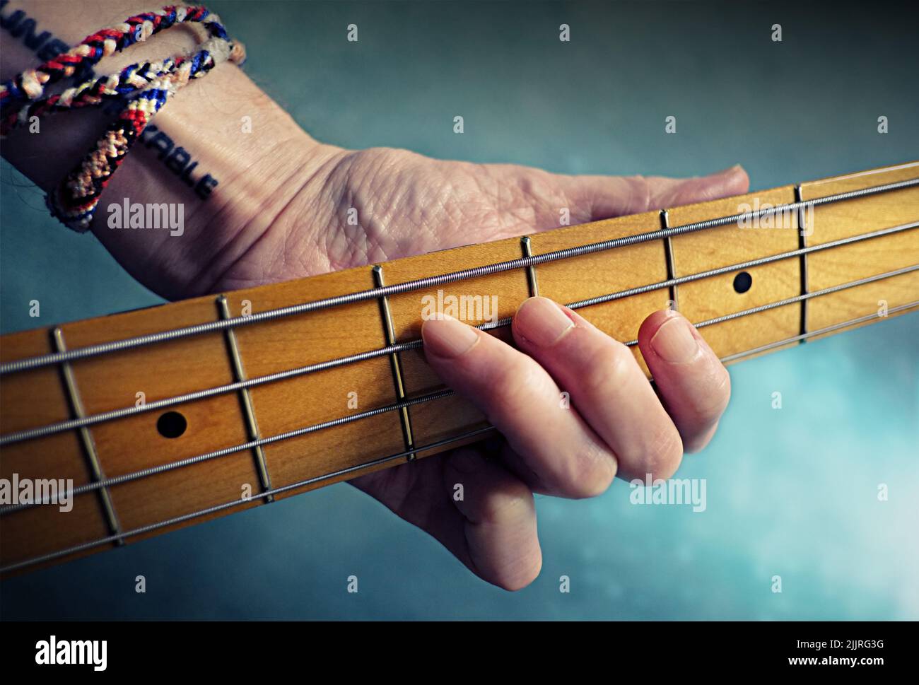 Eine Nahaufnahme einer Hand, die einen Akkord am Hals der Bassgitarre hält - für Hintergründe Stockfoto