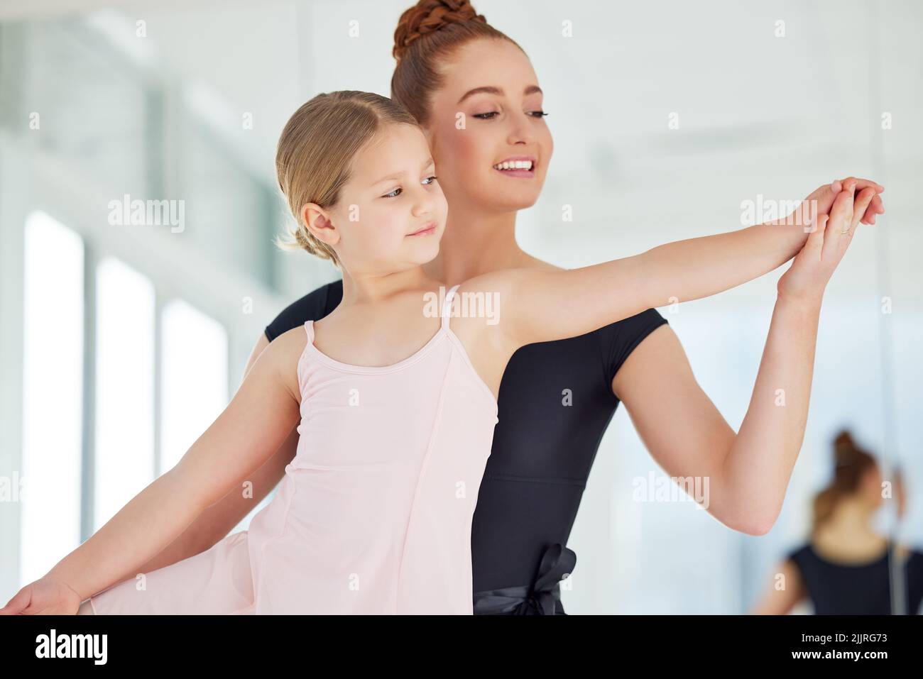 Balletttechnik ist willkürlich und sehr schwierig. Ein kleines Mädchen übt Ballett mit ihrer Lehrerin in einem Tanzstudio. Stockfoto