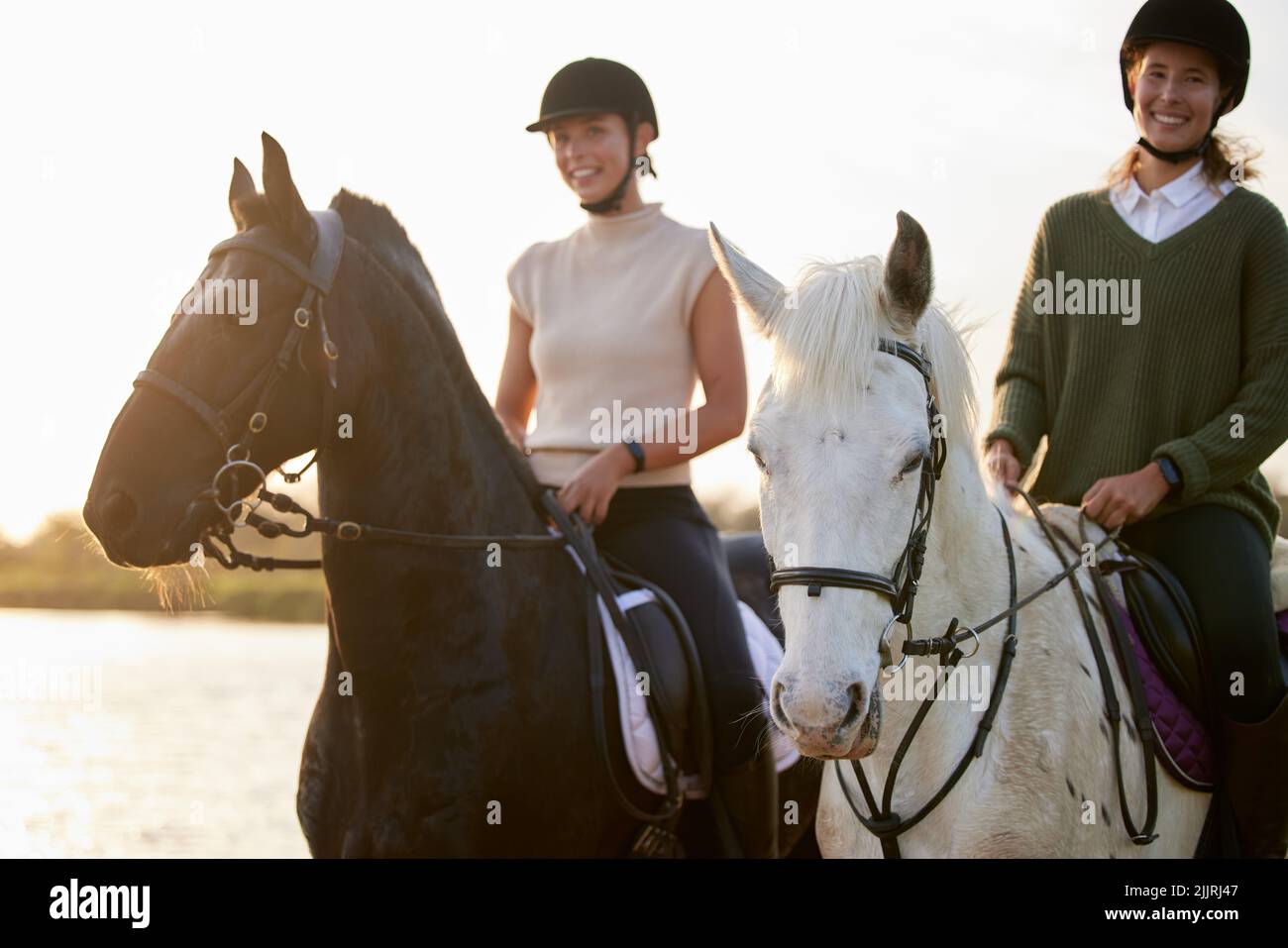 Eine willige Dienerin, aber nie eine Sklavin. Zwei junge Frauen reiten draußen auf einem Feld auf ihren Pferden. Stockfoto