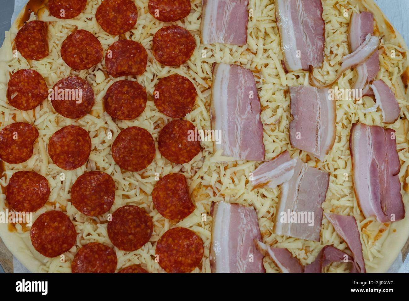 Ein Blick von oben auf eine Pizza, halb Pepperoni und Speck Stockfoto