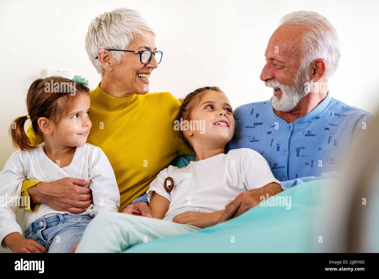 Glückliche Enkelkinder, die Großvater auf der Krankenhausstation besuchen. Support-, Familien- und Gesundheitskonzept. Stockfoto