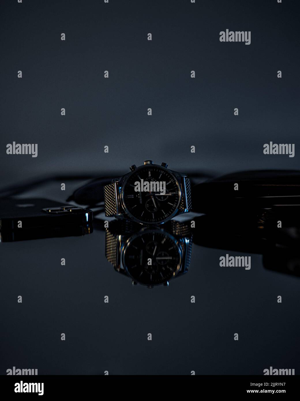 Eine EDC-Uhr und ein schwarzes iPhone mit sichtbaren Reflexionen auf dem Glastisch mit verschwommenem Hintergrund, Deutschland Stockfoto
