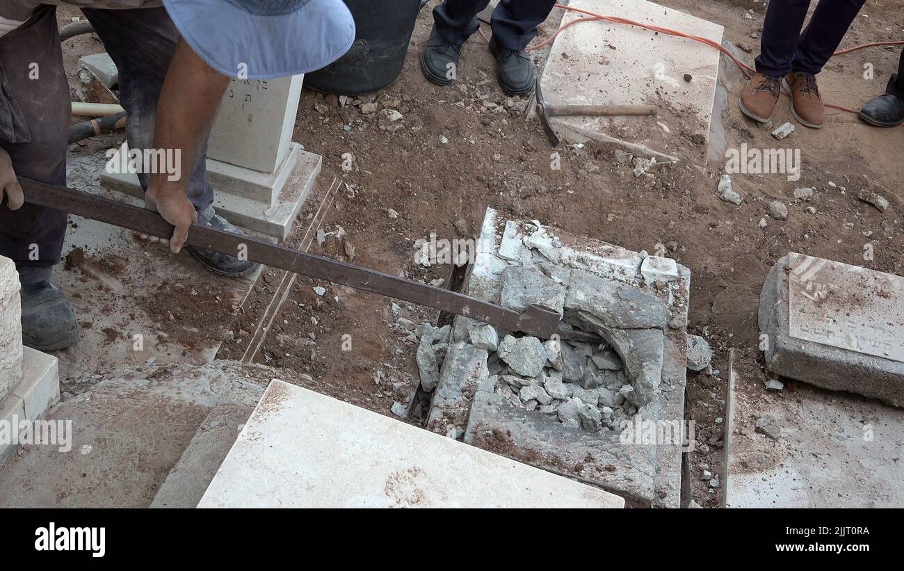 GIVATAYIM, ISRAEL - 27. JULI: Ein Arbeiter öffnet das Grab von Yosef Melamed, einem 1949 verstorbenen jemenitischen Kind, für die Entnahme einer DNA-Probe auf dem Friedhof Nahalat-Jitzhak am 27. Juli 2022 in Givatayim, Israel. Das Grab wurde geöffnet, um der Familie des Jungen zu beweisen, dass er dort begraben ist und nicht entführt und zur Adoption aufgelegt wurde. In den 1950s Jahren in Israel verschwanden jemenitische Kinder, deren Eltern behaupteten, ihre Kinder seien in der sogenannten jemenitischen KinderAffäre „entführt“ worden. Kredit: Eddie Gerald/Alamy Live Nachrichten Stockfoto