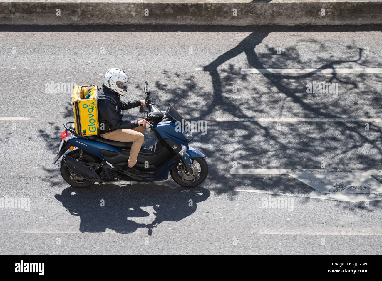 Ein Kurier der Firma Glovo, der Paket auf einem Motorrad in Lissabon, Portugal, ausliefert Stockfoto