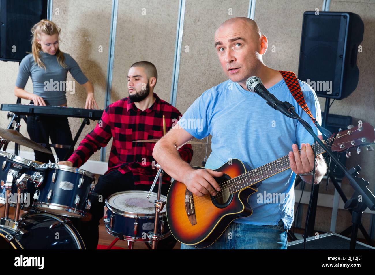 Probe der Musikgruppe. Bandleader spielt Gitarre und singt mit seinen Musikern im Aufnahmestudio Stockfoto