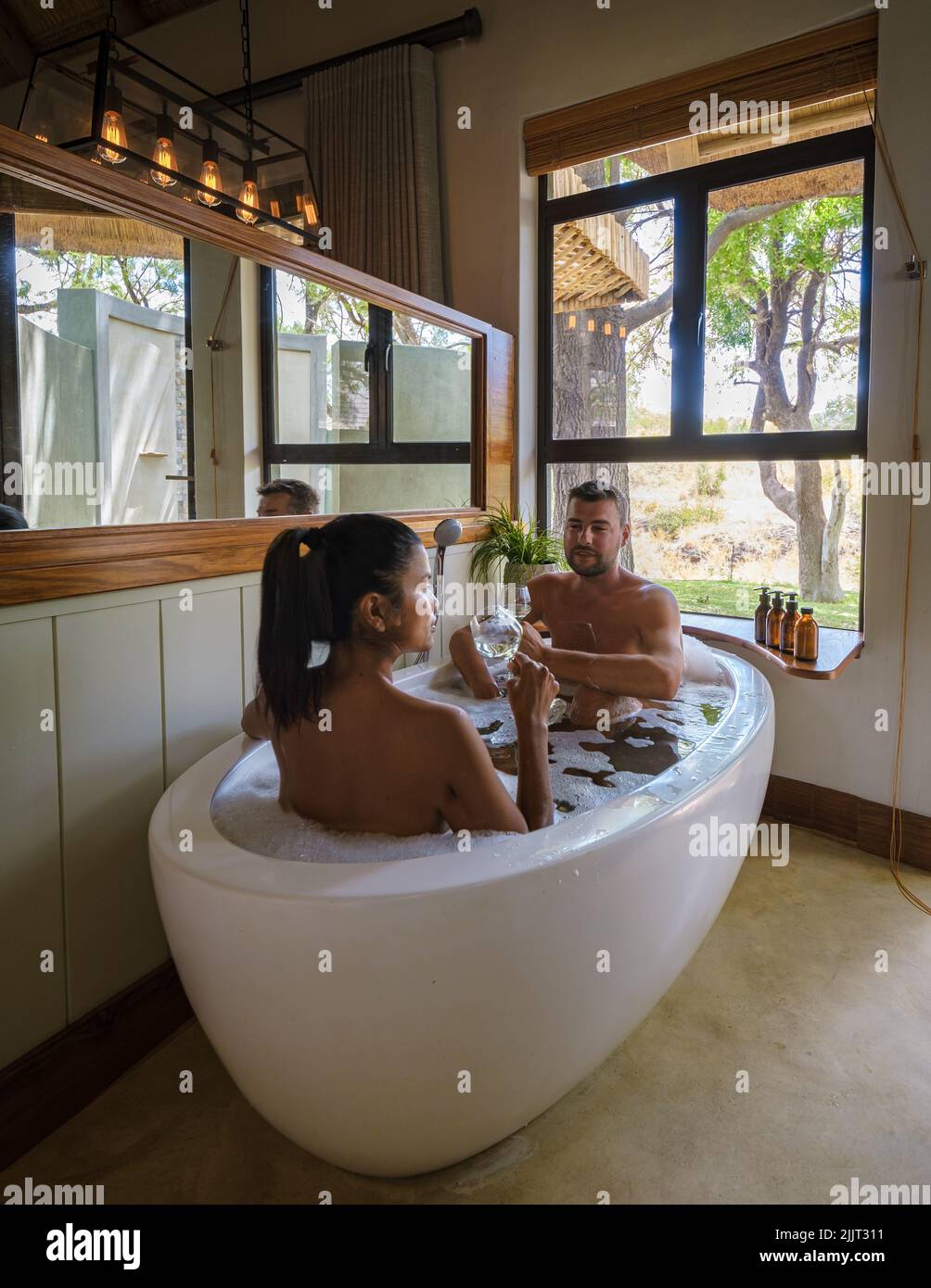 Männer und Frauen in einer Badewanne, ein Paar auf Safari in Südafrika in einer Luxus-Safari-Lodge. Männer und Frauen entspannen im Bad Stockfoto