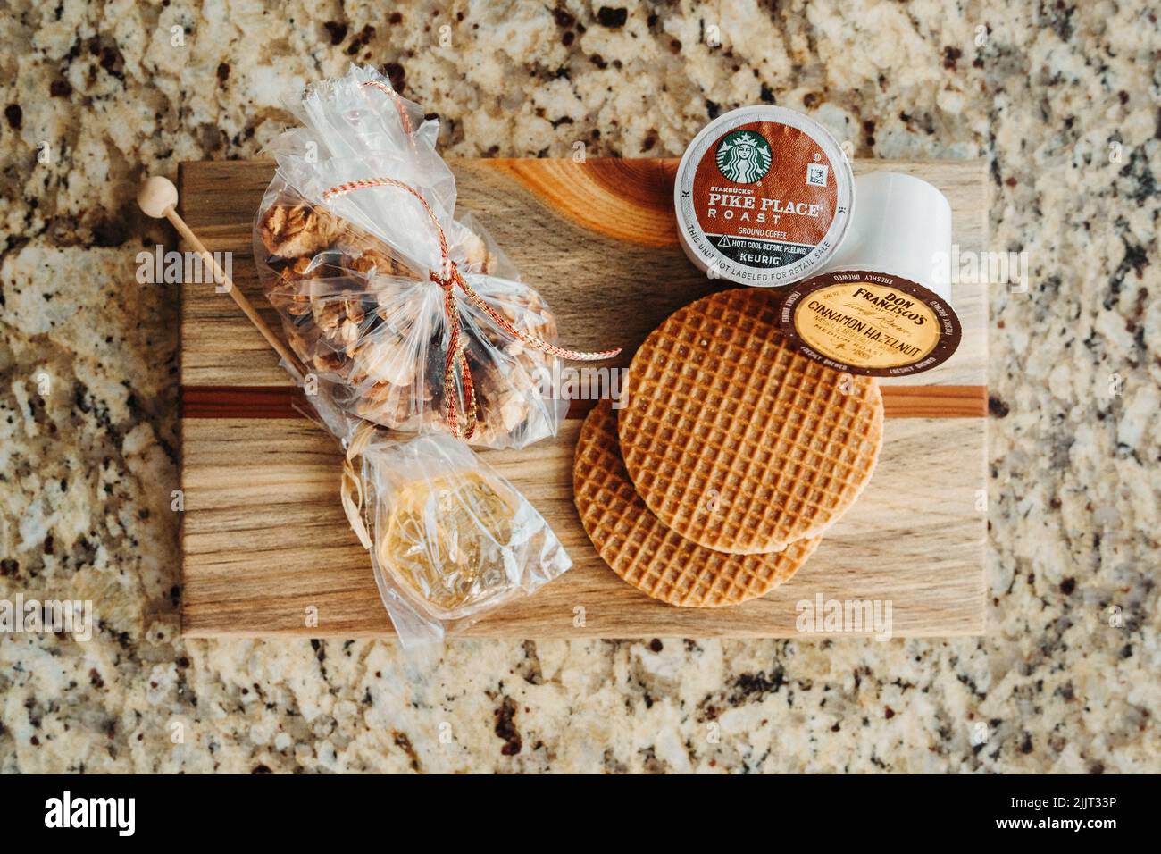 Ein Holzkochbrett mit Nüssen, Honigrührer, Waffelplätzchen, Starbucks K-Cup-Kaffeepods Stockfoto