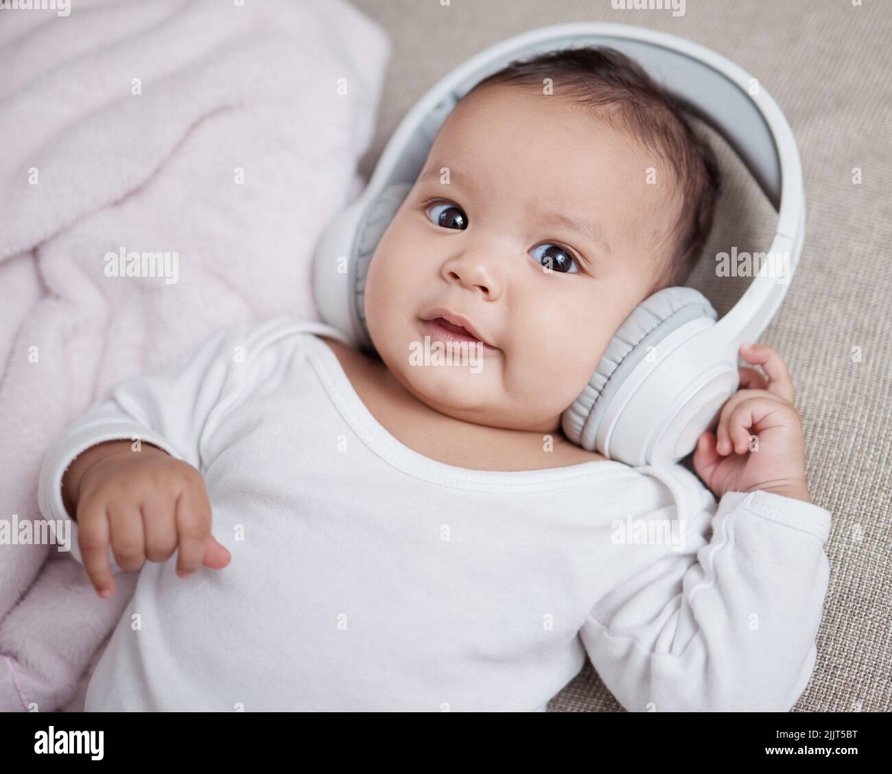 Musik macht einen großen Unterschied für das Baby-Gehirn. Aufnahme eines entzückenden Babys, das zuhause Kopfhörer trägt. Stockfoto