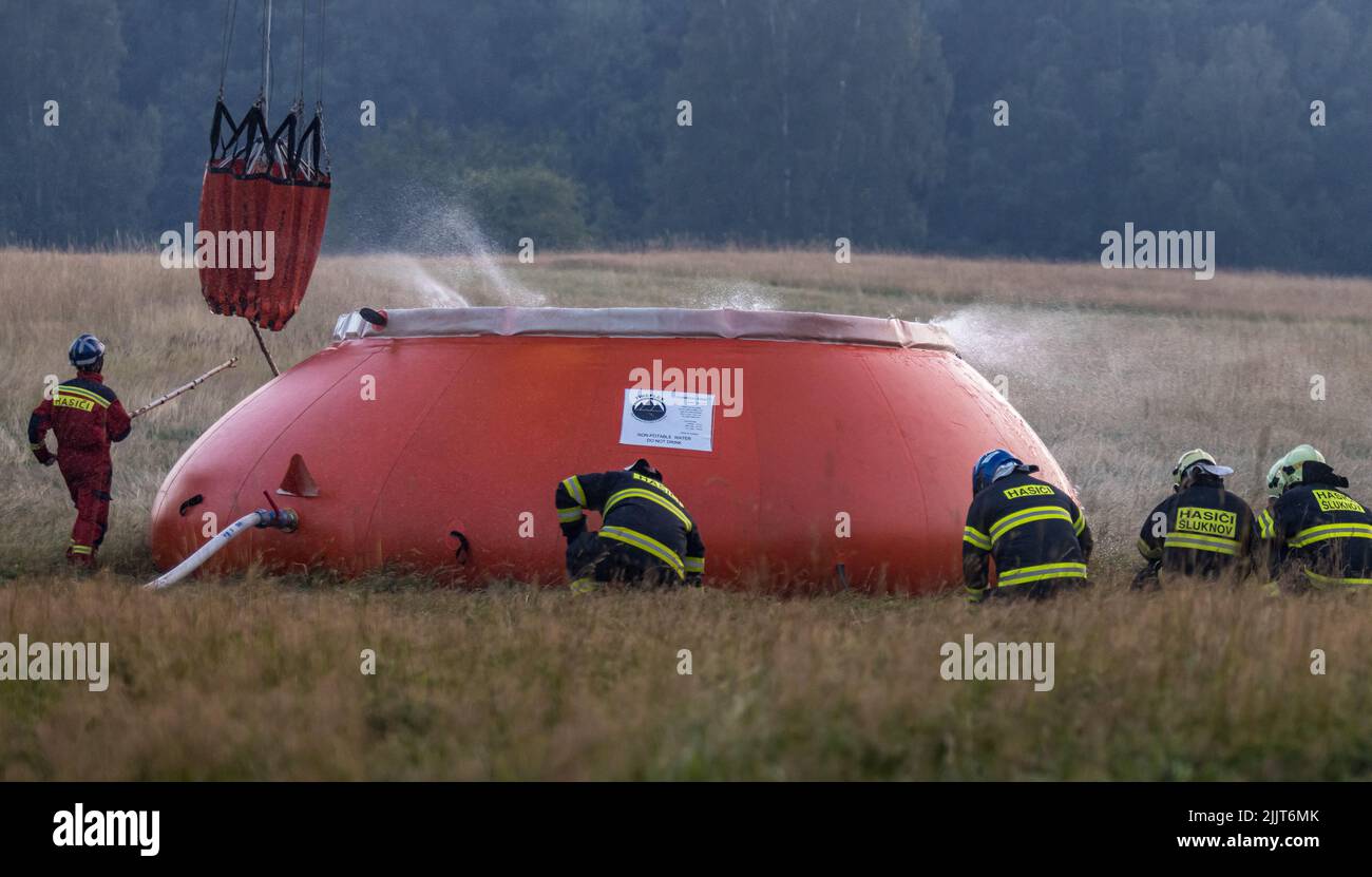 Hrensko, Tschechische Republik. 27.. Juli 2022. Helikopter bringt Wasser aus einem speziellen 54,5-Kubikmeter-Beutel, der sich in der Nähe des Feuers befindet und von Tankern befüllt wird, Hratsko im Nationalpark Ceske Svycarsko (Tschechische Schweiz), Tschechische Republik, 27. Juli 2022. Das Feuer im Nationalpark hat sich bereits zum vierten Tag in Folge ausgebreitet. Kredit: Vojtech Hajek/CTK Foto/Alamy Live Nachrichten Stockfoto