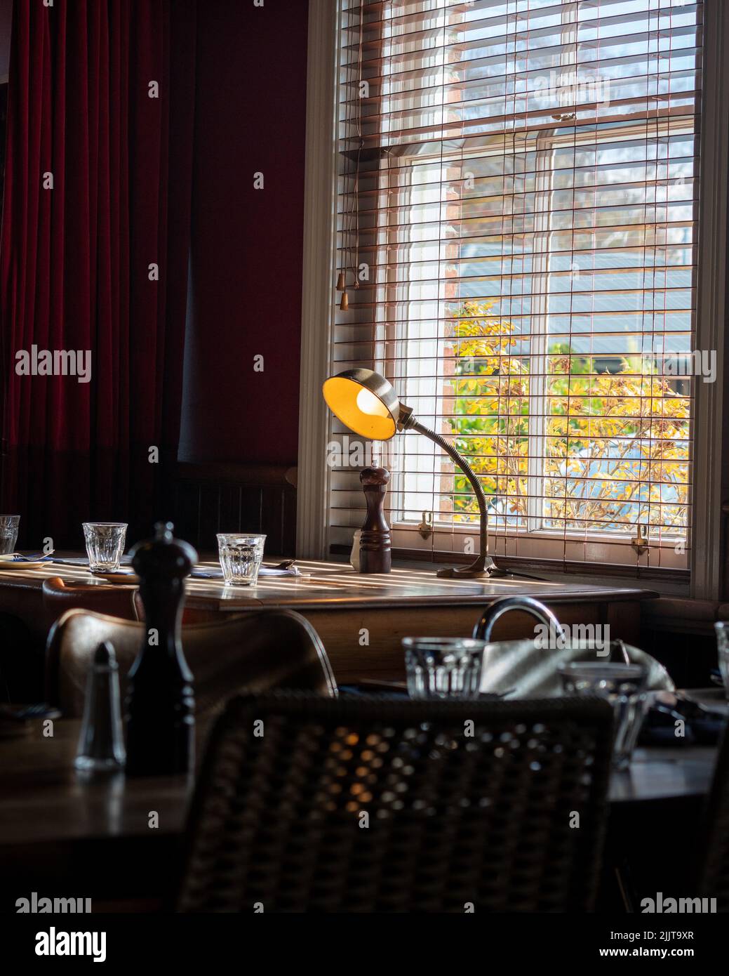 Eine Tischlampe leuchtet an einem leeren Tisch im Laboratory Bar Pub in Lincoln, Neuseeland Stockfoto