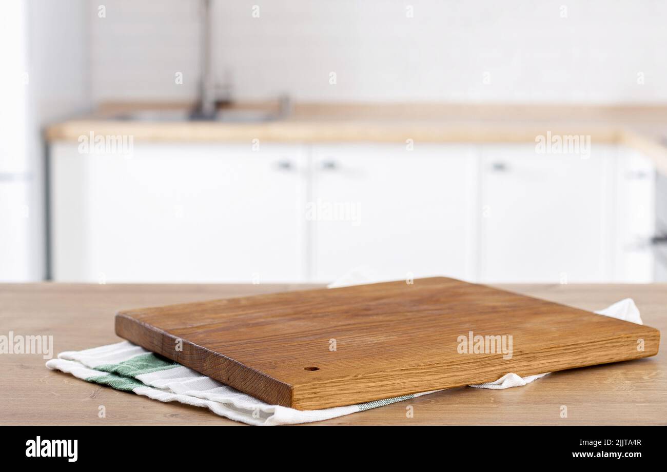 Schneidebrett für die Küche auf dem Küchentisch auf unscharfer Küchenhintergrund mit Platz für die Montage der Produktanzeige Stockfoto