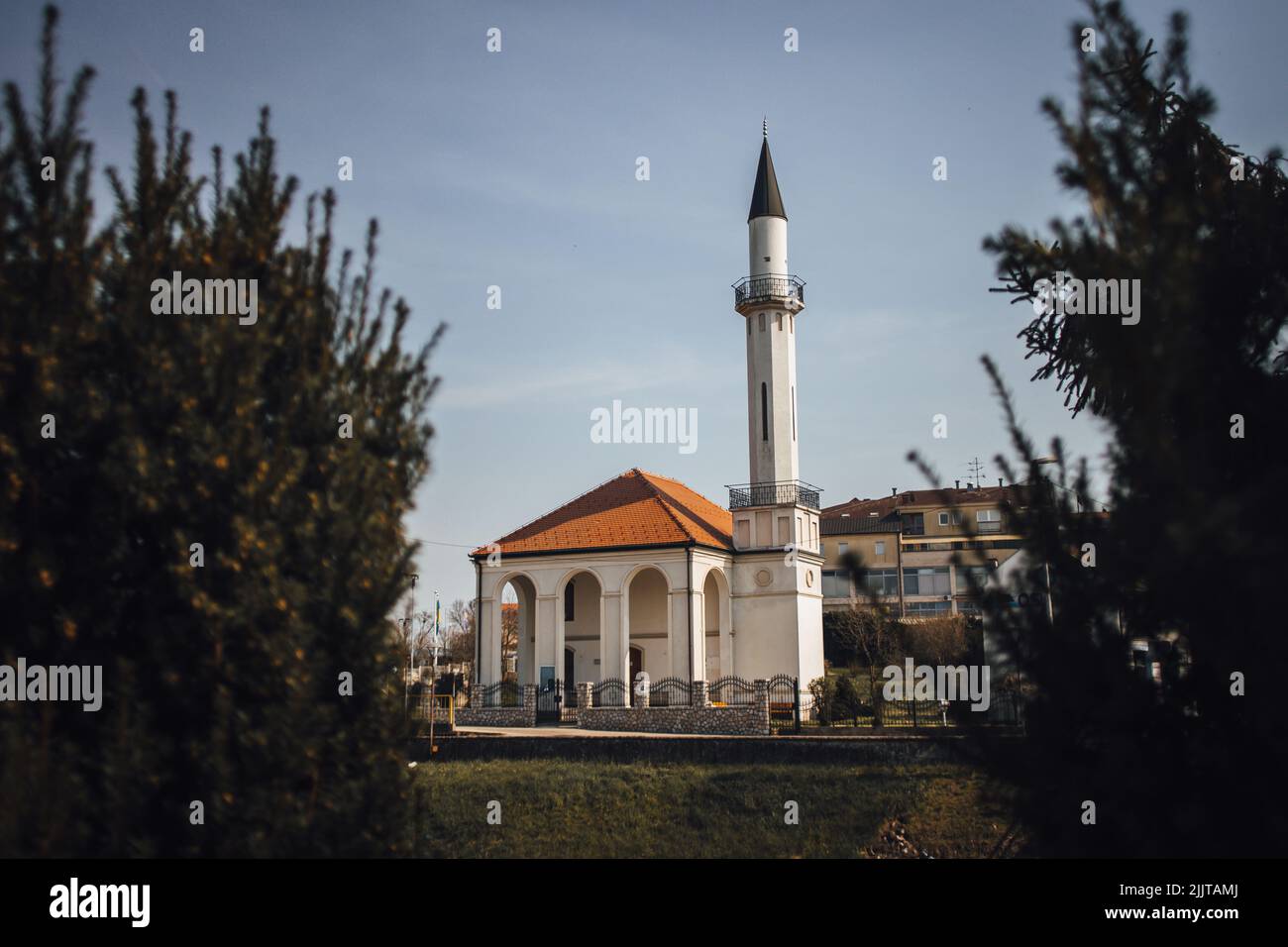 Das äußere Design der Atik Moschee hinter Bäumen auf Kosten des Flusses Sava unter bewölktem Himmel in Brcko, Bosnien und Herzegowina Stockfoto