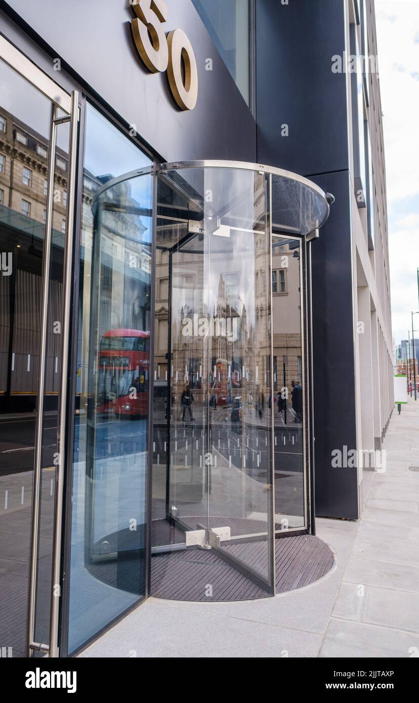 Drehtür aus Glas mit Reflexionen, 50 Eastbourne Terrace, neues Geschäftsgebäude mit gemischter Nutzung gegenüber der Paddington Station, London, Großbritannien. Stockfoto