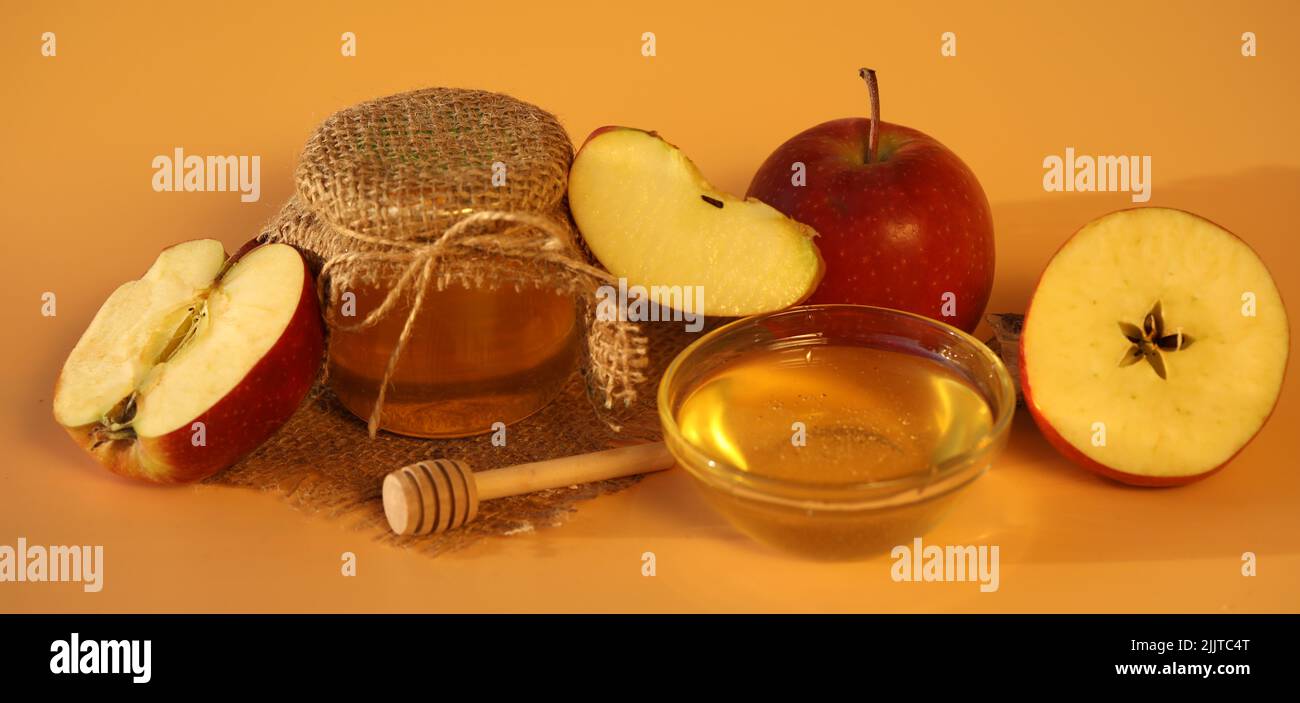 Rote frische Äpfel mit Honig auf gelbem Hintergrund mit Kopierplatz. Apfelfest Stockfoto