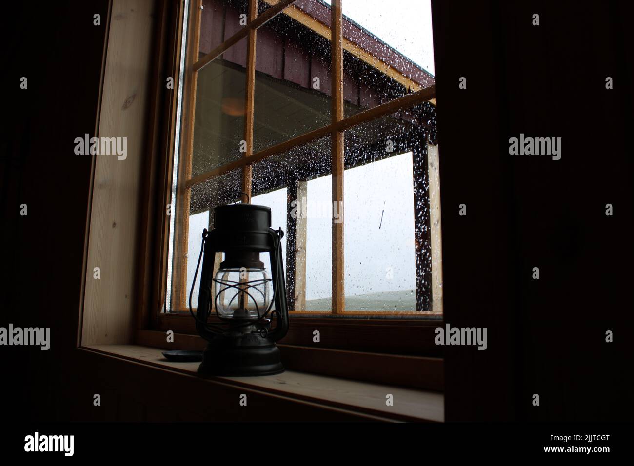 Eine Nahaufnahme einer alten schwarzen Öltischlampe auf einer hölzernen Fensterbank Stockfoto