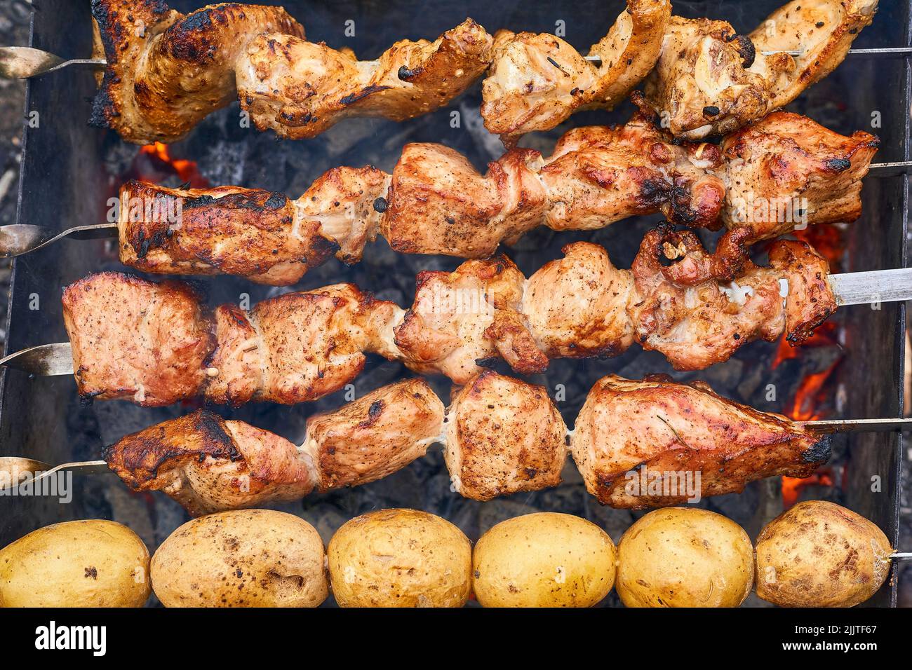 Köstliches Stück Fleisch und Kartoffeln gebraten über dem Feuer bei einem Picknick. Stockfoto