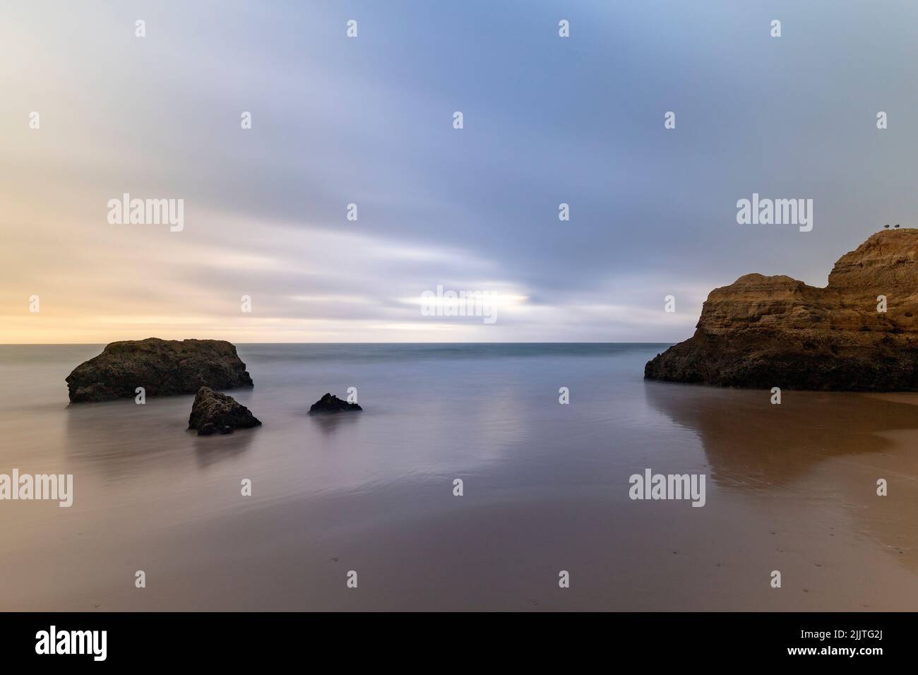 Eine wunderschöne Aufnahme von riesigen Felsen auf einem nassen Sand am leeren Strand Stockfoto