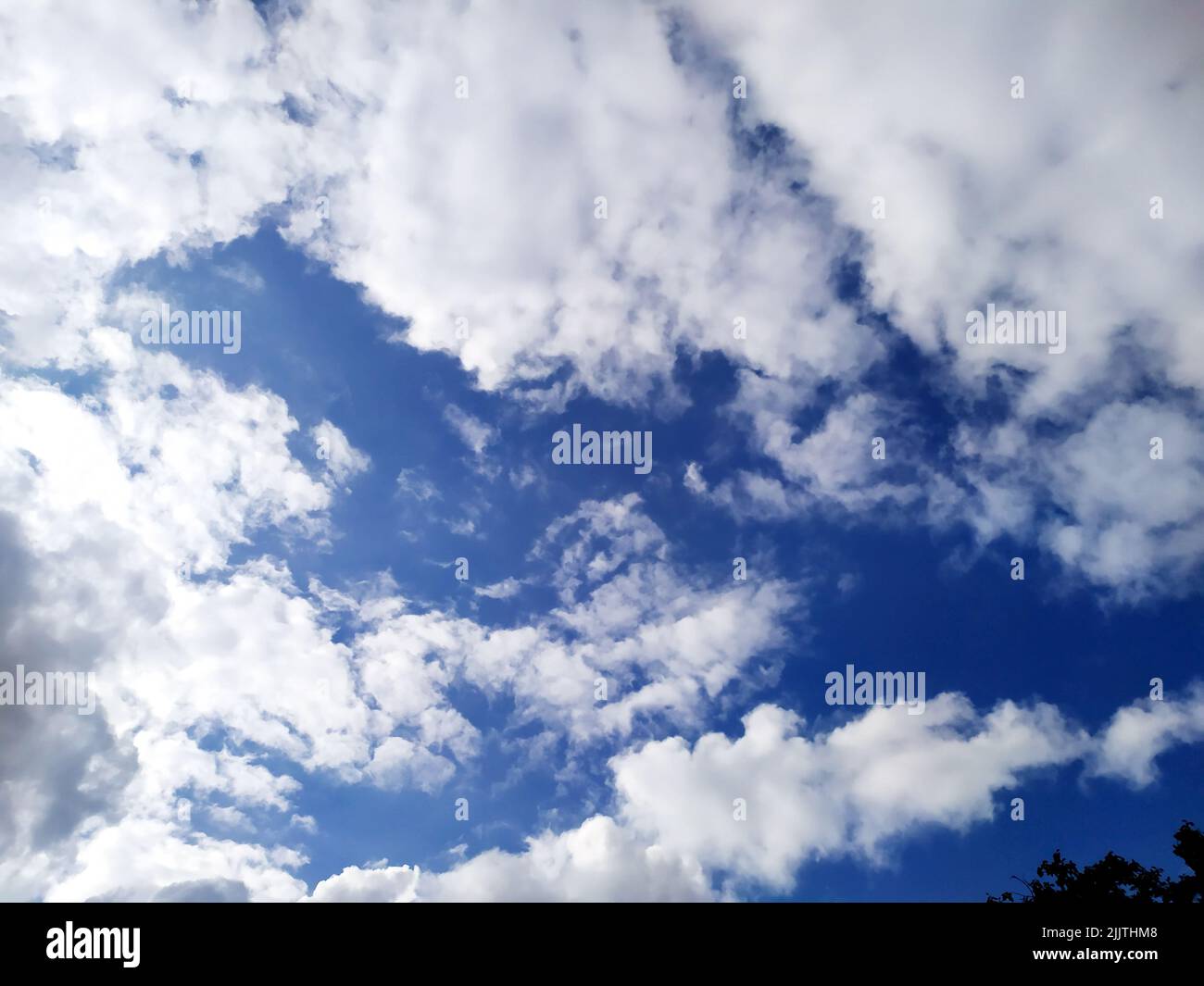 Weiße Wolken fliegen am blauen Himmel Stockfoto