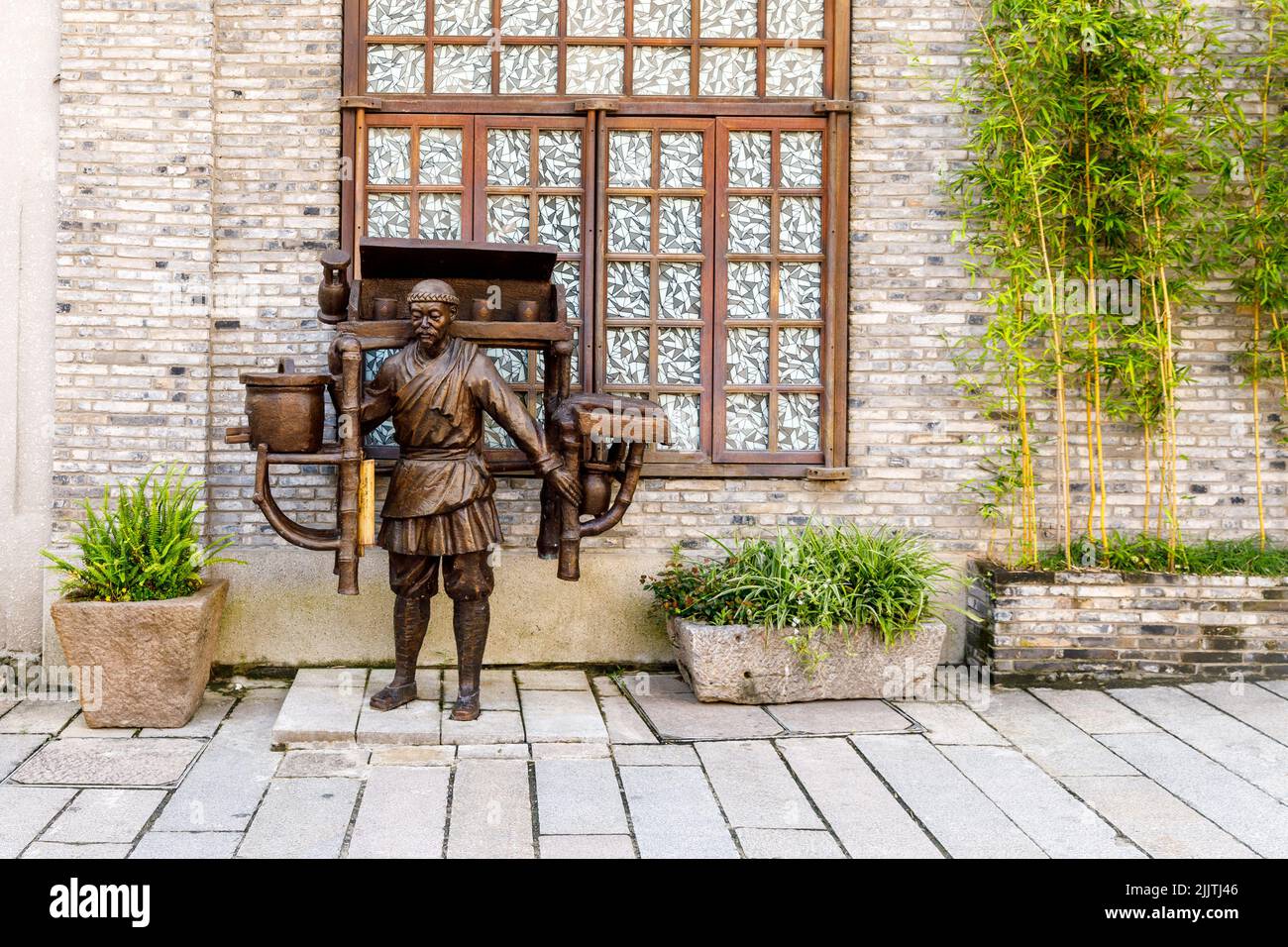 Wenzhou, China - 24. Juli 2022: Bronzeskulptur mit einem männlichen Abbild, das ein Objekt über seinen Schultern trägt. Stockfoto