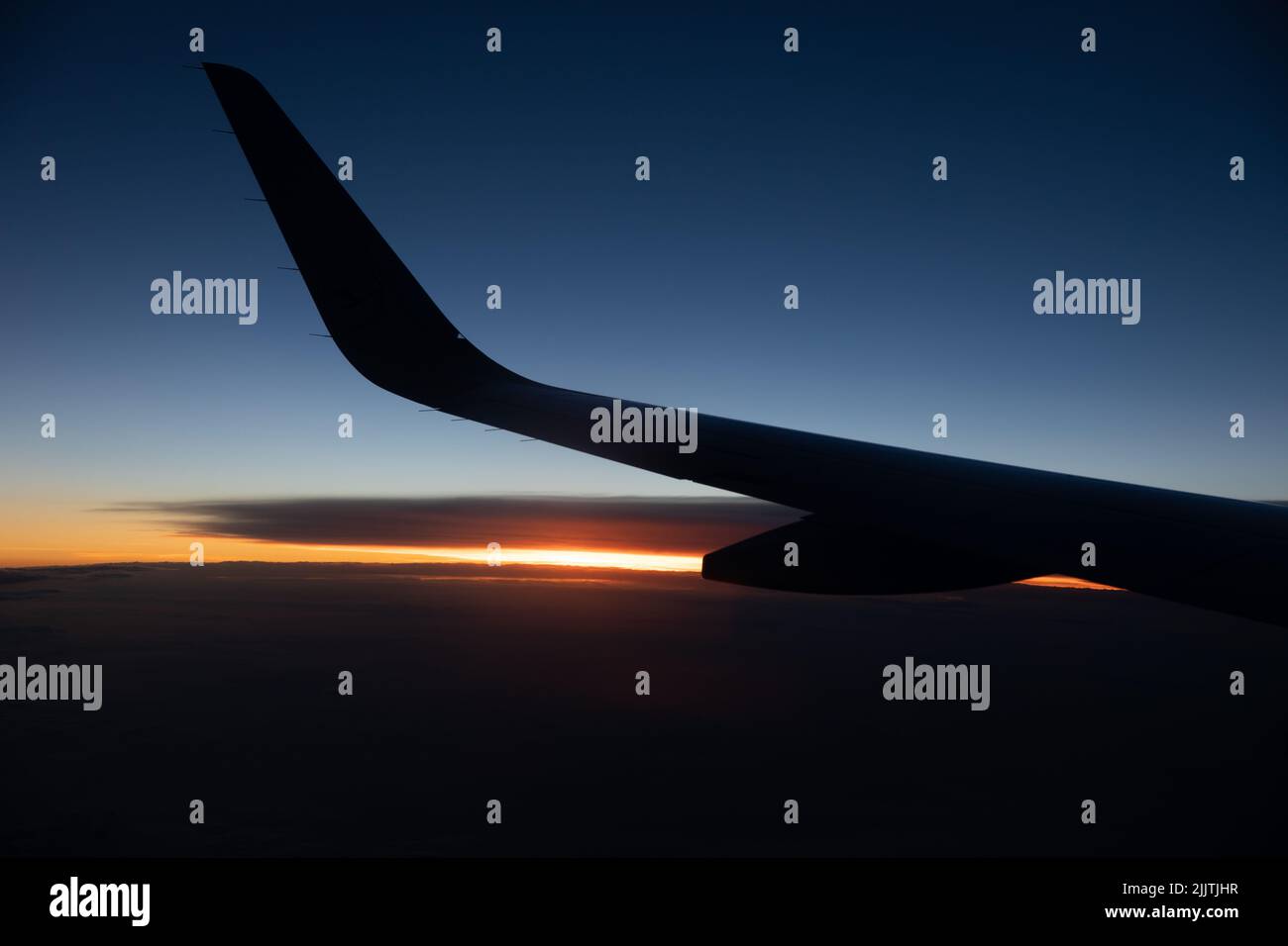 Die Silhouette des linken Flügels und des Flügelbeines eines Flugzeugs gegen eine goldene Stunde Stockfoto