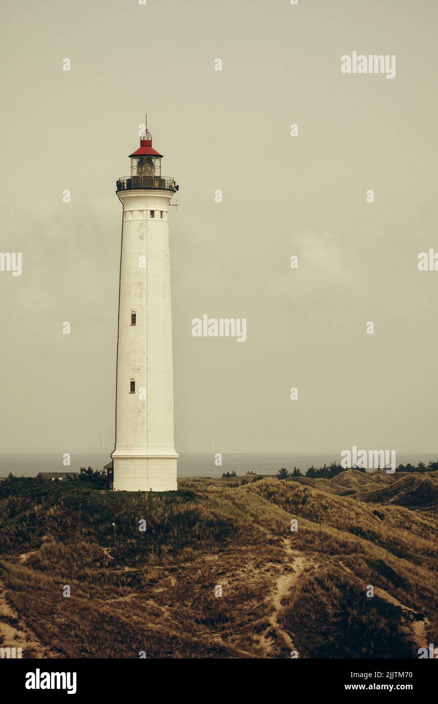Eine vertikale Aufnahme eines weißen Leuchtturms vor einem grau bewölkten Himmel Stockfoto