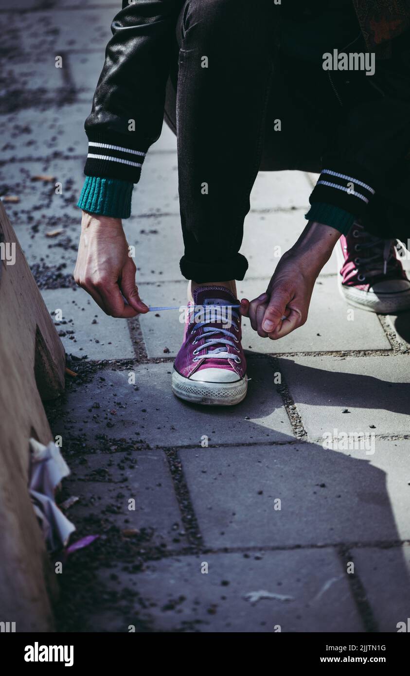 Eine vertikale Aufnahme einer Person, die purpurne Schuhe bindet Stockfoto