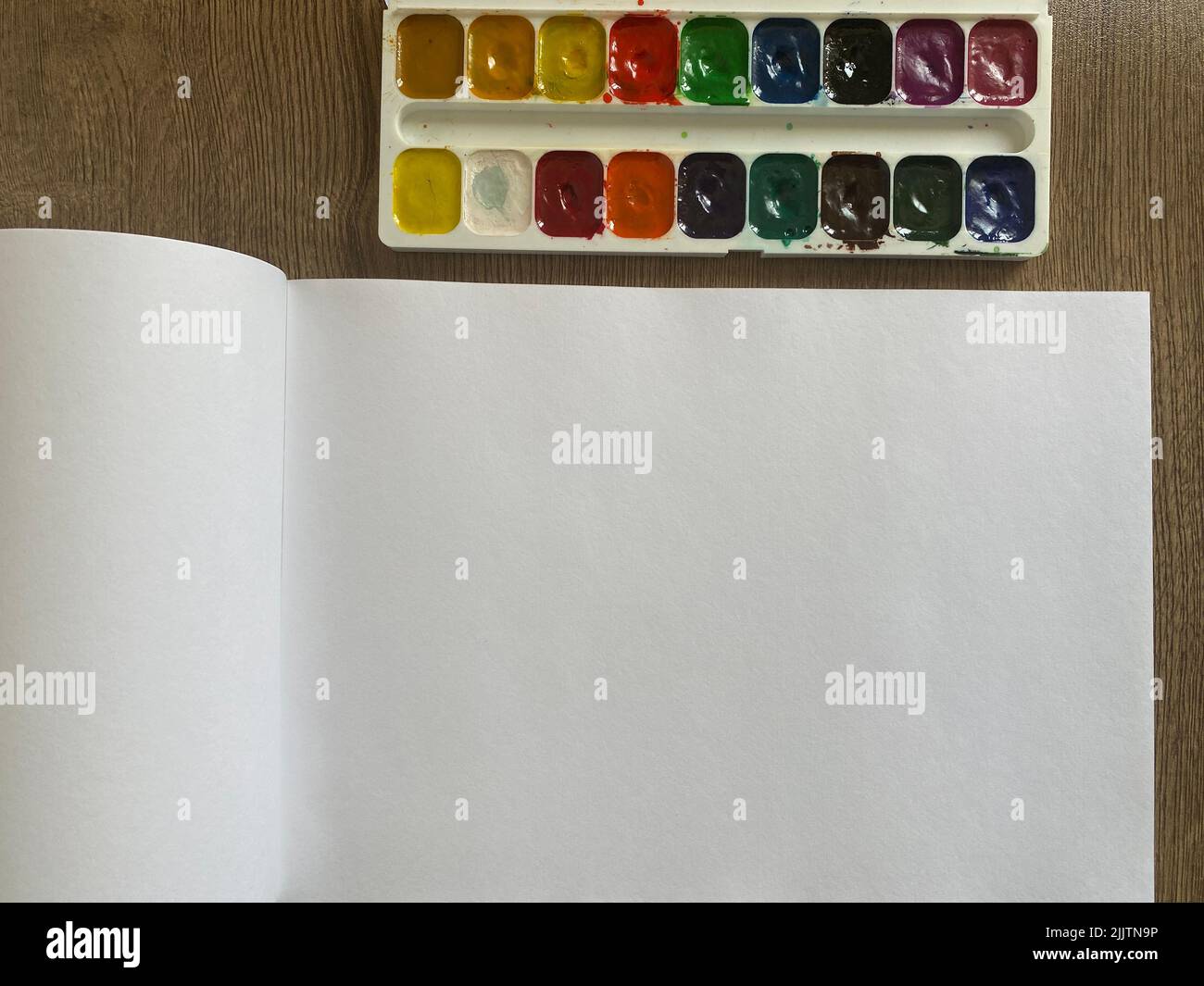 Das Aquarell malt mit weißen Albumseiten auf einen Holztisch Stockfoto